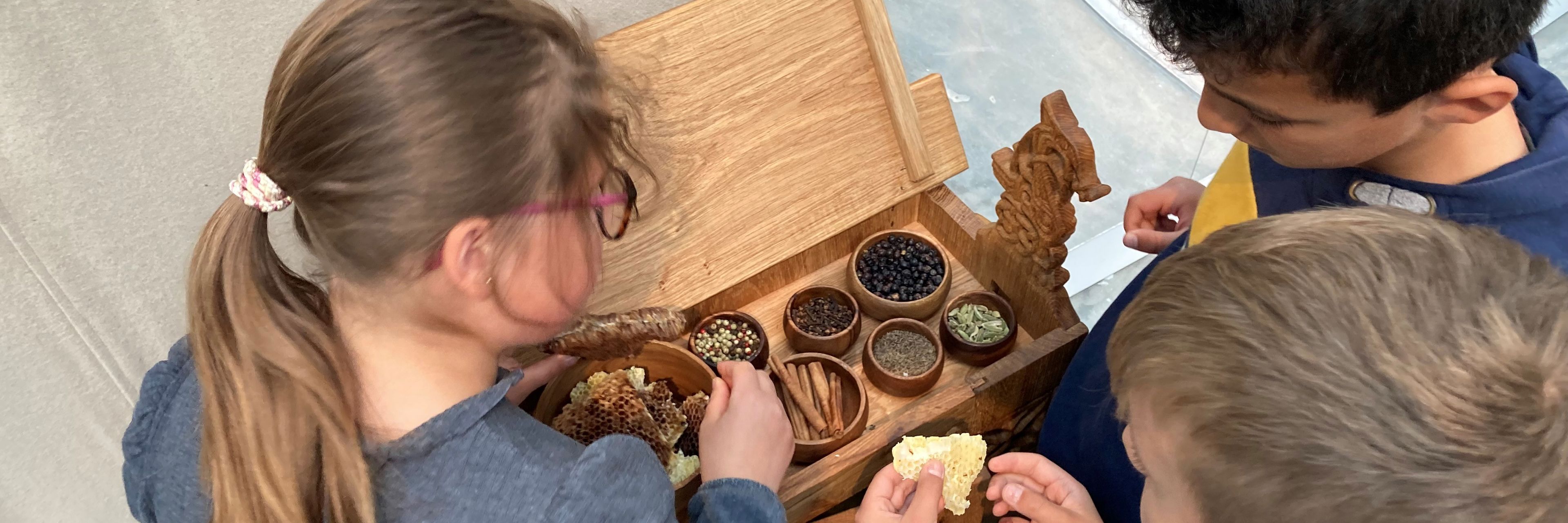 Tre børn dufter og mærker i udstillingen Magt og guld